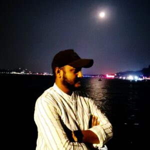 A man standing in front of a body of water with a full moon in the background.