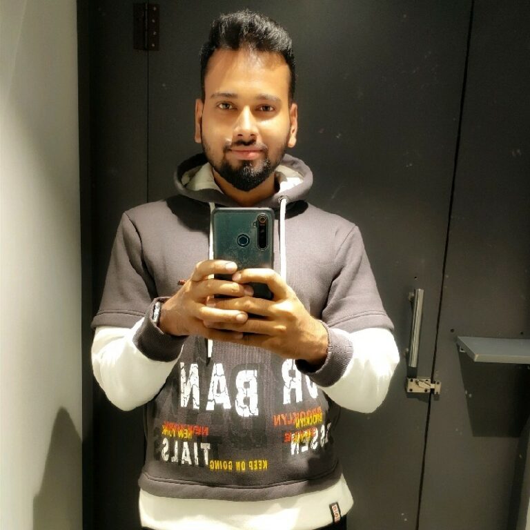 A man in a hoodie taking a selfie in a mirror.