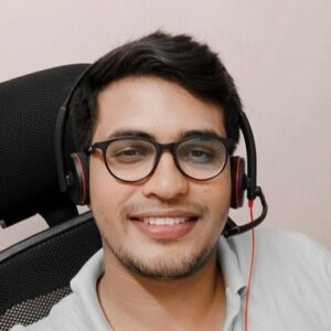 A man wearing glasses and a headset is smiling.