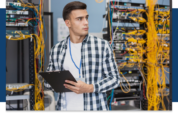 A man with a clipboard in front of a rack of servers.